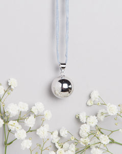 polished silver plated Mexican bola pregnancy necklace on light grey hand dyed silk cord